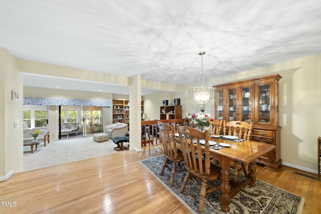 dining space featuring a chandelier, light wood-style floors, and baseboards