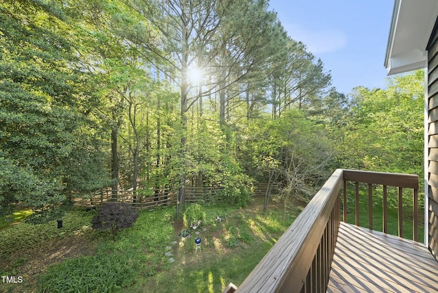wooden terrace featuring fence and a wooded view