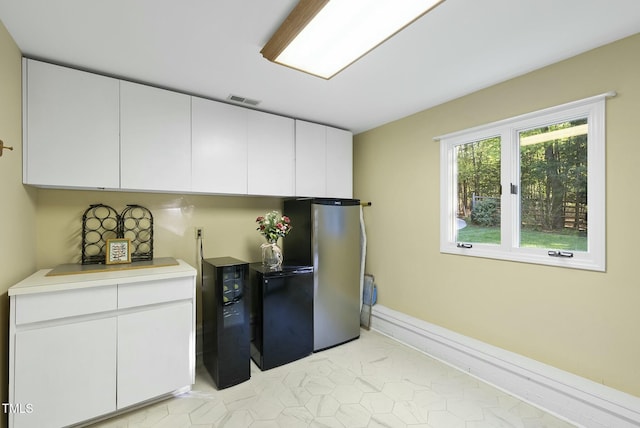 kitchen with freestanding refrigerator, white cabinets, light countertops, and light tile patterned floors