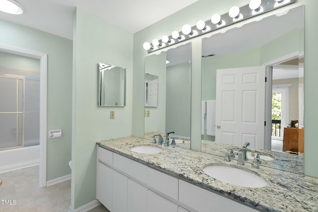 bathroom featuring double vanity, baseboards, bath / shower combo with glass door, and ensuite bathroom