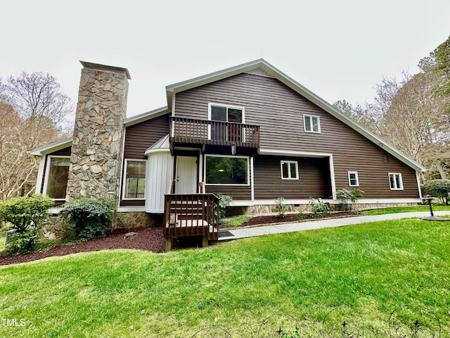 back of property with a balcony, a lawn, and a chimney