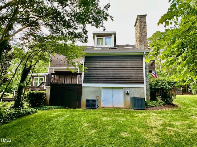 rear view of house featuring cooling unit, a yard, a chimney, and a deck