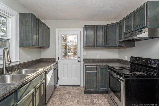 kitchen featuring dark countertops, appliances with stainless steel finishes, under cabinet range hood, and a sink