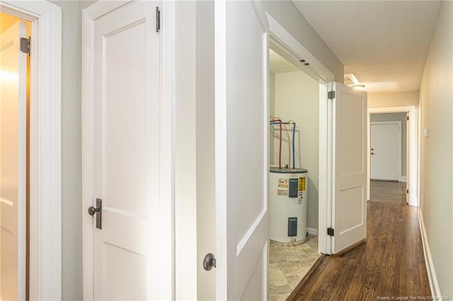 hall with dark wood finished floors, baseboards, and electric water heater
