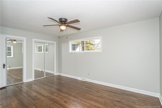 unfurnished bedroom featuring baseboards, dark wood-style flooring, and multiple windows