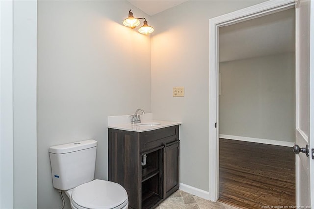 half bathroom with toilet, vanity, and baseboards