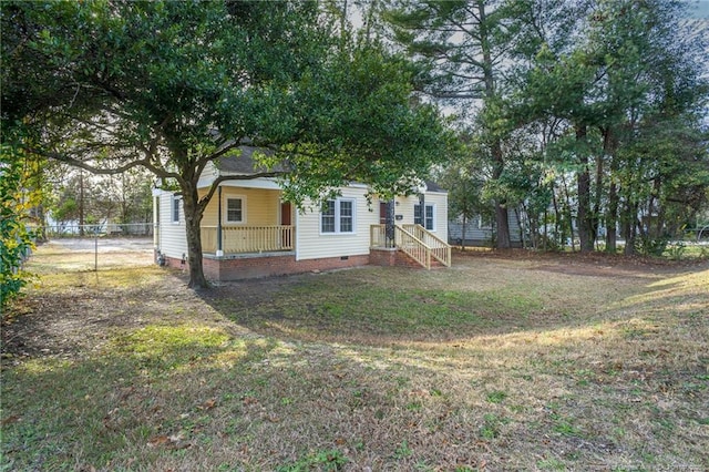 back of property featuring covered porch, a lawn, crawl space, and fence