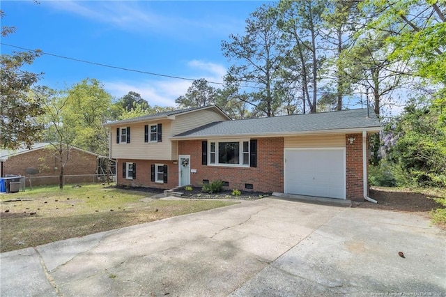 split level home featuring fence, an attached garage, driveway, a front lawn, and brick siding