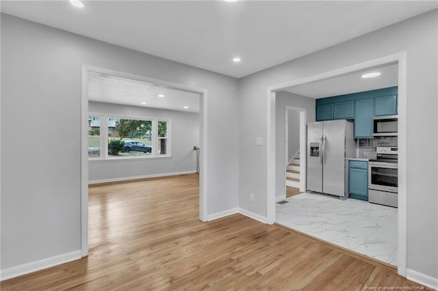 interior space with marble finish floor, blue cabinets, baseboards, and appliances with stainless steel finishes