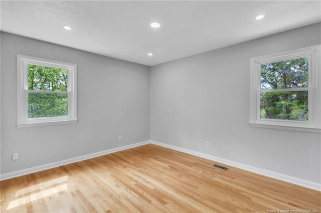 unfurnished room with baseboards, visible vents, wood finished floors, and recessed lighting