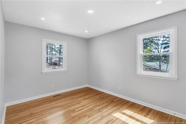 unfurnished room with baseboards, light wood-style flooring, visible vents, and plenty of natural light