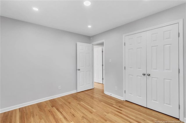 unfurnished bedroom with a closet, baseboards, light wood finished floors, and recessed lighting