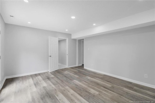 empty room with recessed lighting, baseboards, and wood finished floors
