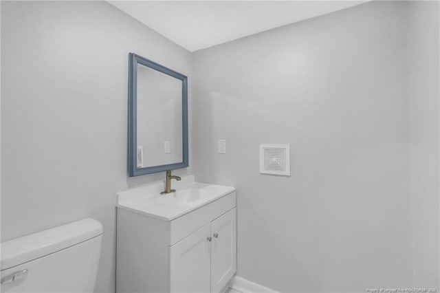 half bath featuring baseboards, toilet, and vanity