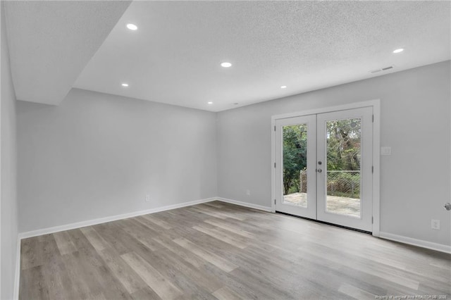 empty room featuring baseboards, visible vents, wood finished floors, and french doors