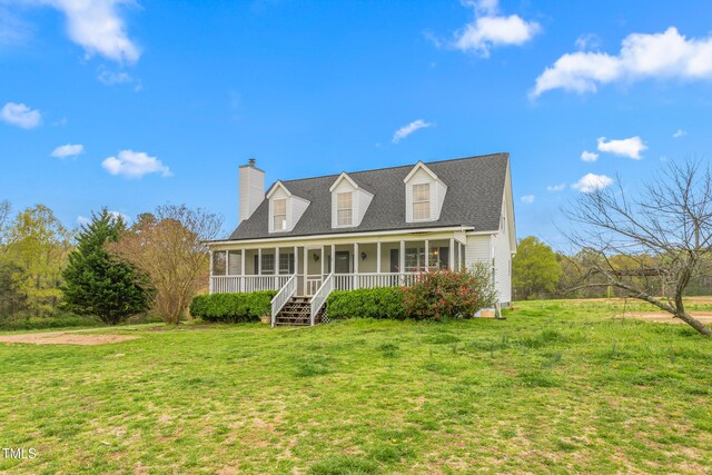 new england style home featuring a chimney, a porch, and a front lawn