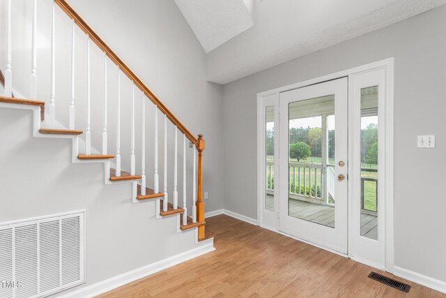 foyer featuring visible vents, stairway, and wood finished floors