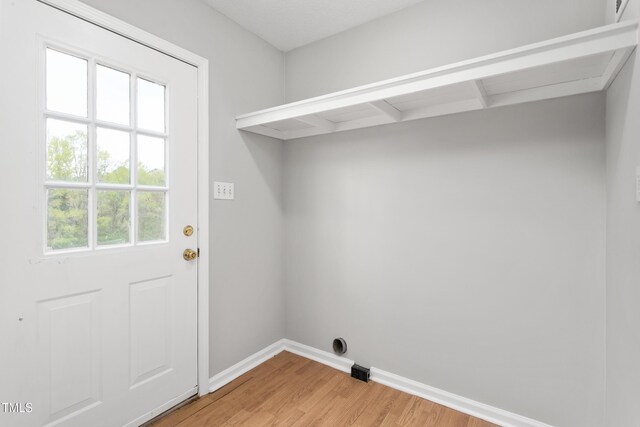 clothes washing area with baseboards, laundry area, and light wood-type flooring