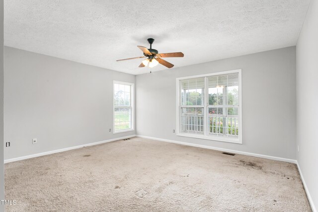 carpeted spare room with baseboards, a textured ceiling, ceiling fan, and visible vents
