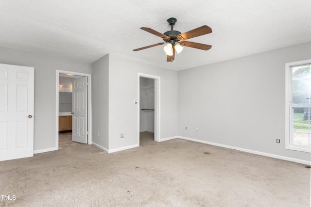 unfurnished bedroom with baseboards, carpet floors, a textured ceiling, and a walk in closet