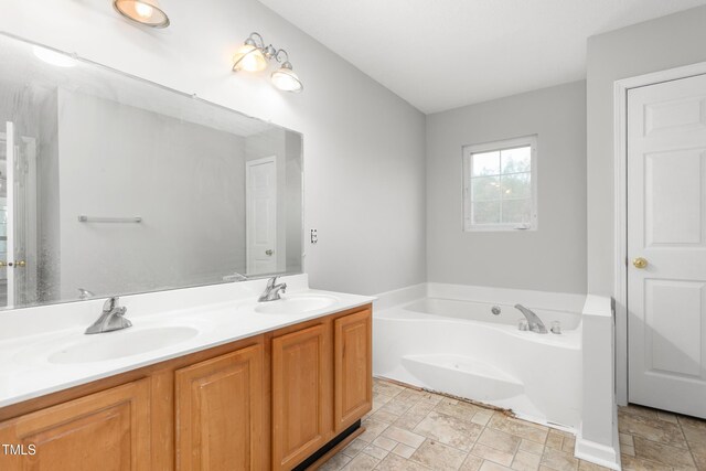 full bath with a bath, double vanity, a sink, and stone finish floor