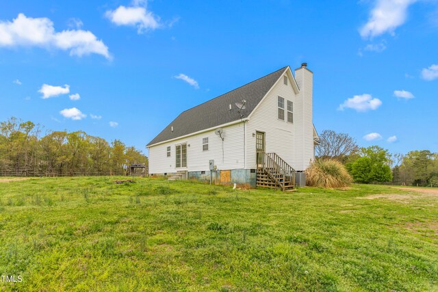 rear view of property with a chimney, a shingled roof, a yard, and entry steps