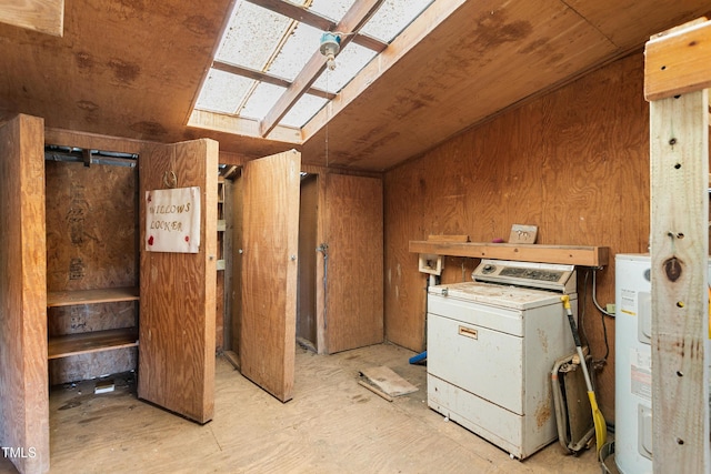 interior space featuring electric water heater, wooden walls, washer / dryer, and vaulted ceiling with skylight