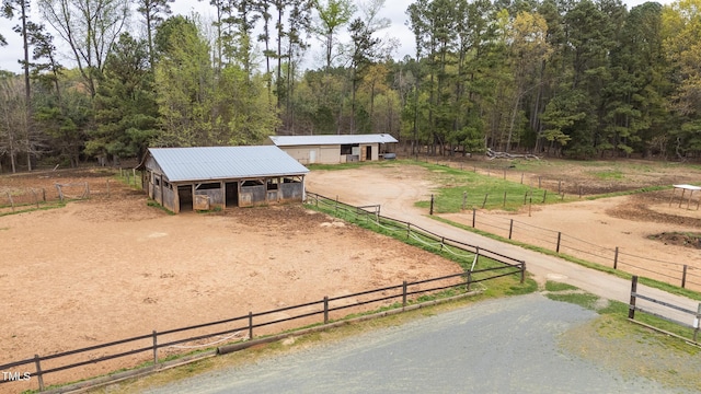 view of property's community with an outdoor structure, a rural view, driveway, an exterior structure, and a view of trees