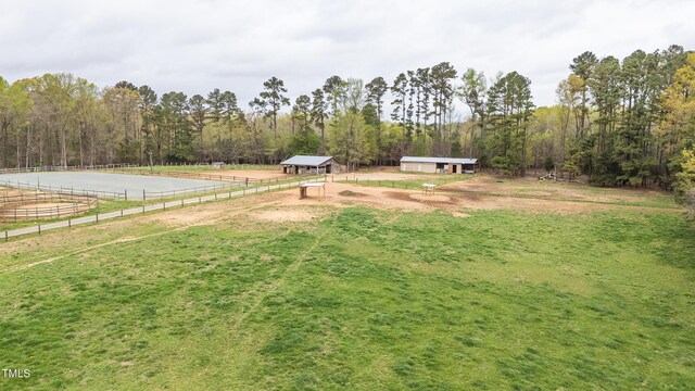 view of yard with fence, an enclosed area, an outdoor structure, a rural view, and a forest view