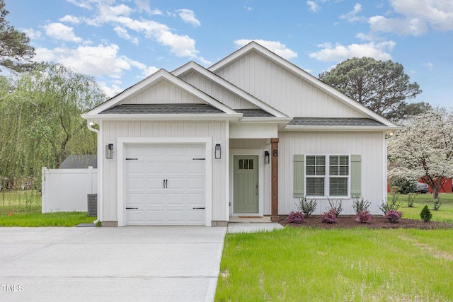 view of front of home with concrete driveway, a shingled roof, an attached garage, fence, and a front yard