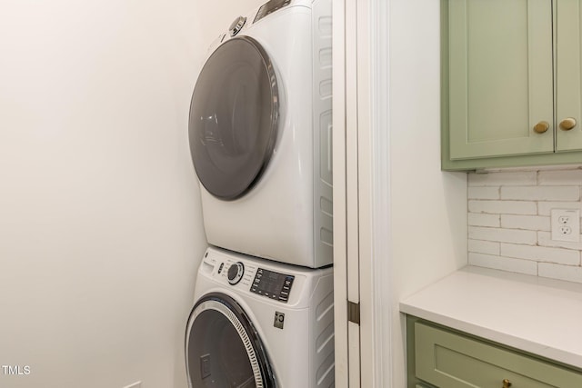 clothes washing area with stacked washer and clothes dryer and cabinet space