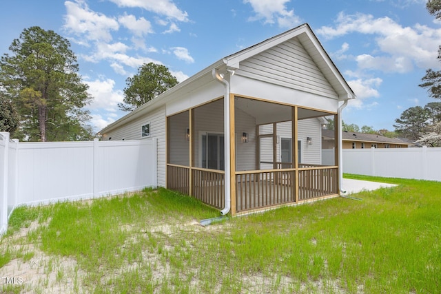 rear view of house with fence, a lawn, and a sunroom