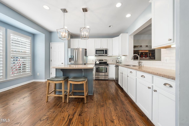 kitchen with stainless steel appliances, a sink, a chandelier, a kitchen island, and backsplash