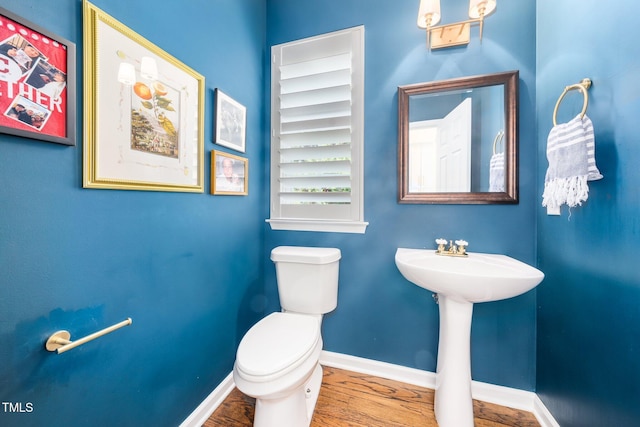 bathroom with wood finished floors, toilet, baseboards, and a sink