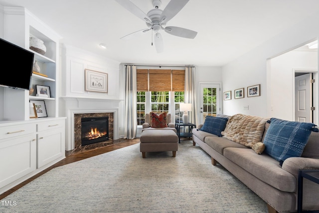 living area featuring a premium fireplace, a ceiling fan, and wood finished floors