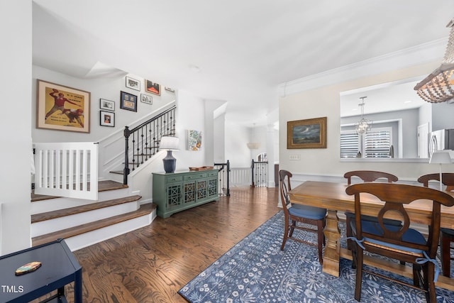 dining space with wood finished floors, stairway, and a chandelier