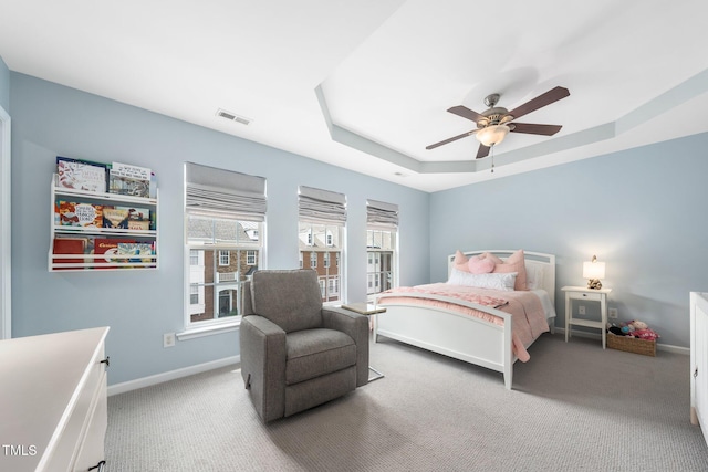carpeted bedroom with a tray ceiling, baseboards, and a ceiling fan