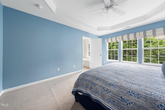 bedroom with a raised ceiling, baseboards, ornamental molding, carpet floors, and ensuite bath