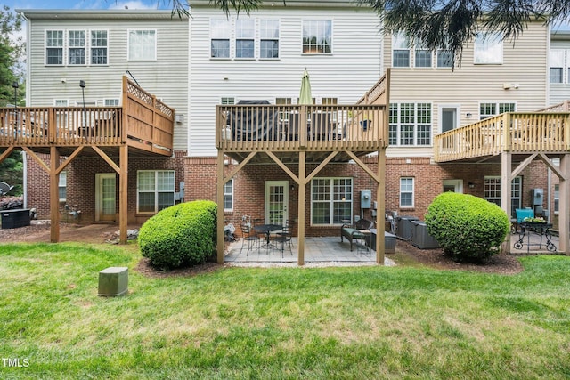 back of property with a yard, a deck, and a patio
