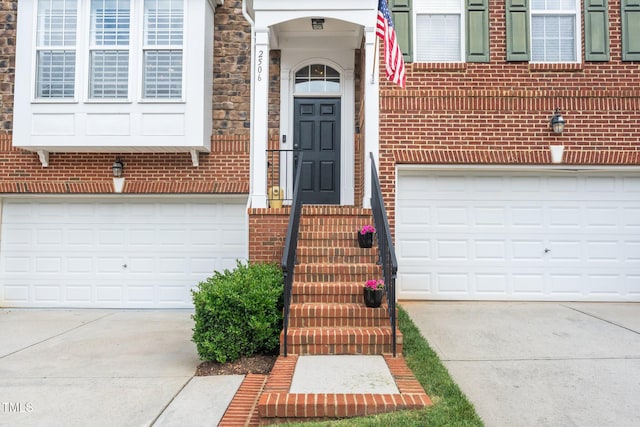 property entrance featuring concrete driveway, a garage, and brick siding