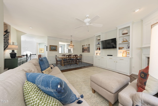 carpeted living area with a ceiling fan and stairway