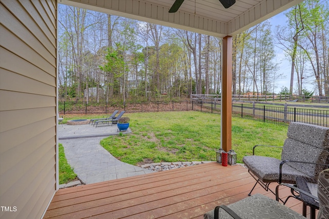 deck with a yard, ceiling fan, a fenced backyard, and a fire pit