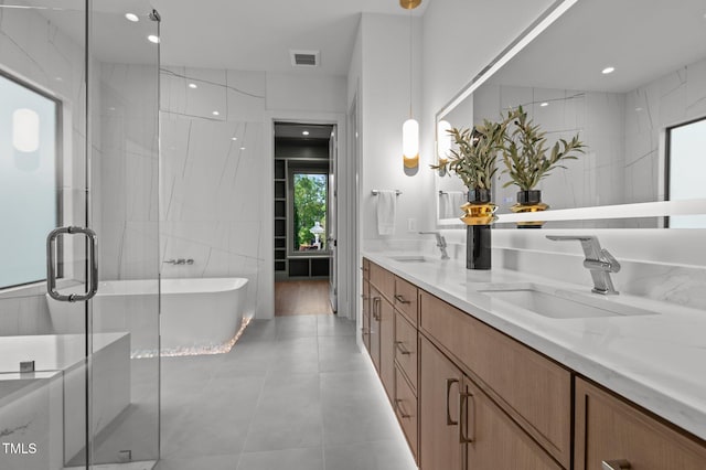 bathroom with a stall shower, a freestanding bath, visible vents, and a sink