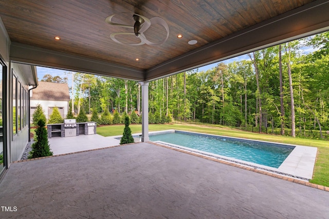 pool with a patio, exterior kitchen, a ceiling fan, and a lawn