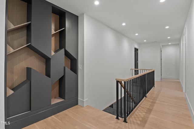 corridor featuring light wood-style floors, baseboards, an upstairs landing, and recessed lighting