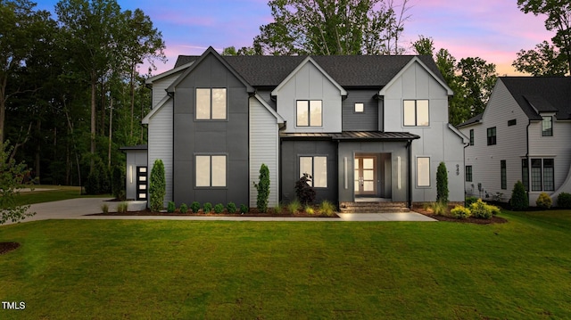 modern farmhouse with a yard, metal roof, a standing seam roof, and board and batten siding