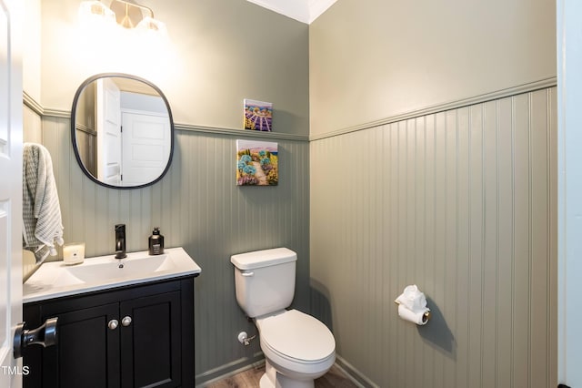 bathroom with toilet, wainscoting, vanity, and wood finished floors