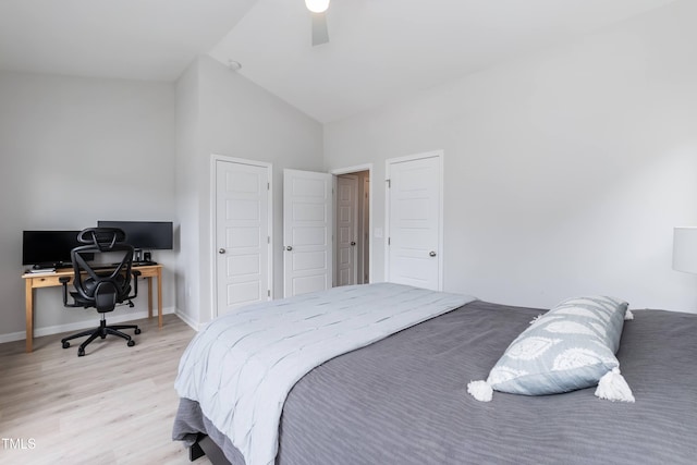 bedroom with light wood-type flooring, lofted ceiling, a desk, baseboards, and ceiling fan