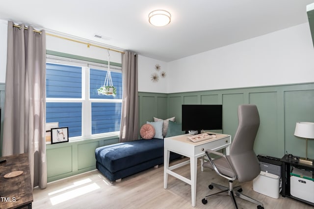 home office with a decorative wall, wainscoting, and light wood finished floors