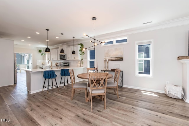 dining area with crown molding, recessed lighting, light wood-type flooring, a chandelier, and baseboards